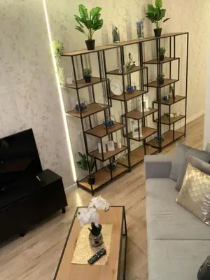 a living room with a couch and shelves with plants at Moderno Apartament in Kraków