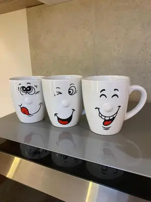 three coffee mugs with faces on them sitting on a counter at Moderno Apartament in Kraków