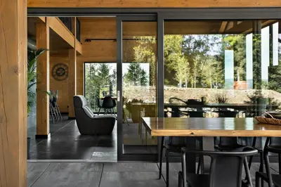 a dining room with glass doors and a table and chairs at Chillout Ślemień nowoczesny dom w górach in Ślemień