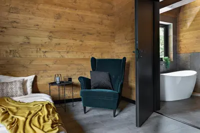 a room with a bed and a chair and a tub at Chillout Ślemień nowoczesny dom w górach in Ślemień