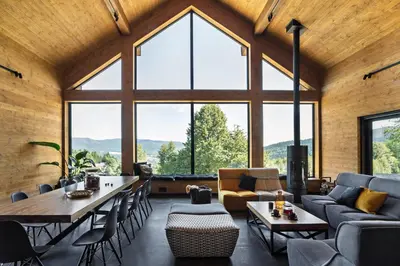 a living room with large windows and a couch and tables at Chillout Ślemień nowoczesny dom w górach in Ślemień