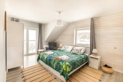a bedroom with a bed and a chair and windows at Bliżej Nieba in Skrzydlna