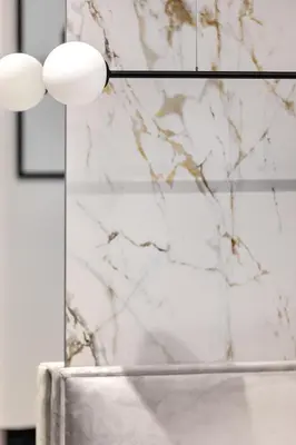 a bathroom with a white marble wall and two lights at Republiki Korczakowskiej Apartamenty in Kraków