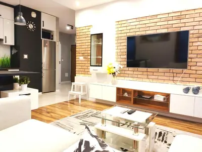 a living room with a large television on a brick wall at Szafrana 5B by Homeprime in Kraków