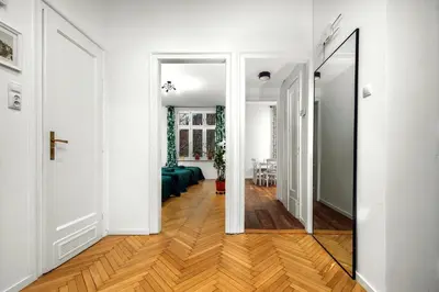 a hallway with white walls and wood floors and a mirror at Apartament blisko Wawelu in Kraków