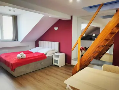 a bedroom with a red bed and a staircase at Apartament Winnica in Kraków