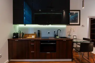 a kitchen with black cabinets and a glass table at Luna Prestige Suite - Old Town Center & Main Station in Kraków