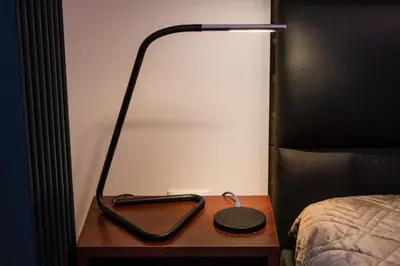 a lamp on a wooden table next to a bed at Luna Prestige Suite - Old Town Center & Main Station in Kraków