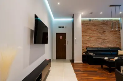 a living room with a couch and a tv on a wall at Luna Prestige Suite - Old Town Center & Main Station in Kraków