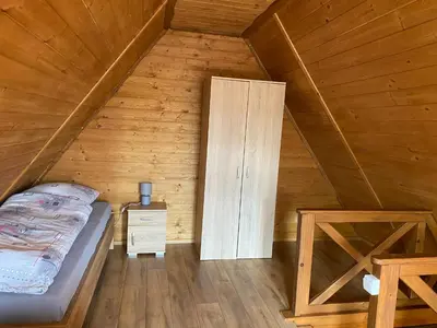 a bedroom with a bed and a cabinet in a attic at Domki- Limanowa, domki z balią i sauną in Limanowa