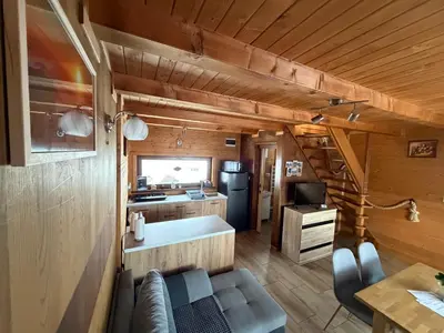 a living room with a couch and a kitchen in a house at Domki- Limanowa, domki z balią i sauną in Limanowa