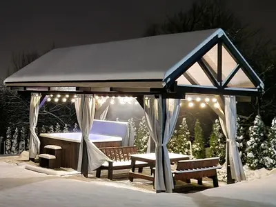 a gazebo with benches and lights in the snow at Domek na Folwarku z jacuzzi in Tarnawa Dolna