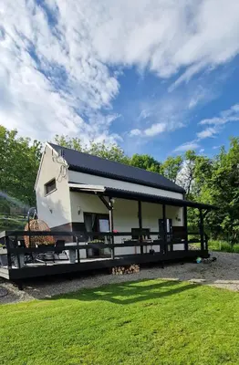 a tiny house with a black roof on a fence at Domek na Folwarku z jacuzzi in Tarnawa Dolna