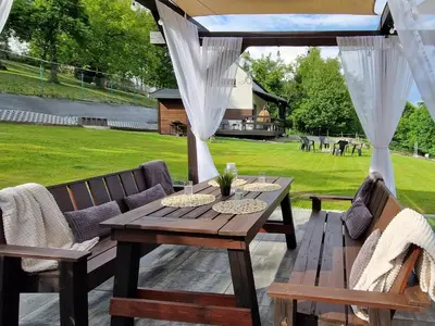 a wooden table and chairs on a patio at Domek na Folwarku z jacuzzi in Tarnawa Dolna