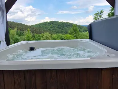 a bath tub with a view of a mountain at Domek na Folwarku z jacuzzi in Tarnawa Dolna
