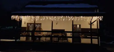 a house with christmas lights hanging from it at night at Domek na Folwarku z jacuzzi in Tarnawa Dolna