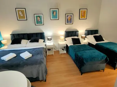 a room with two beds and two tables and pictures on the wall at Hugo VIP Apartments in Kraków