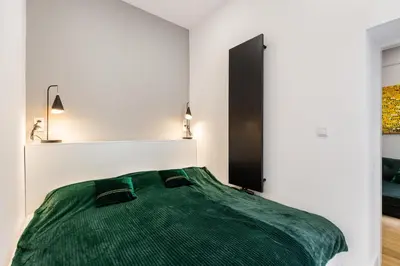 a bedroom with a green bed with two lamps at Oro Apartments in Kraków