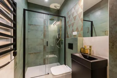 a bathroom with a glass shower and a toilet at Oro Apartments in Kraków