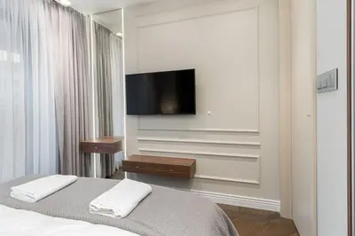 a bedroom with a bed and a tv on a wall at Glossy Apart G244 in Kraków