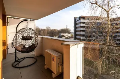 a chair on a balcony with a view of a building at Glossy Apart G244 in Kraków