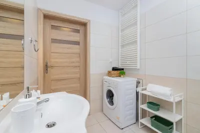 a bathroom with a washing machine and a sink at Bunscha Apartment Dębniki Cracow by Noclegi Renters in Kraków