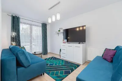 a living room with a blue couch and a tv at Bunscha Apartment Dębniki Cracow by Noclegi Renters in Kraków