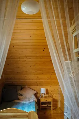 a bed in a room with a wooden ceiling at Alemiło - uroczy dom z balią i widokiem na Babią Górę in Zawoja