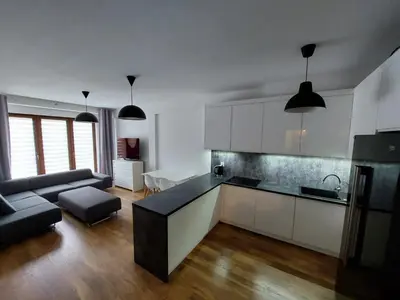 a kitchen with white cabinets and a living room at Apartament Reformacka in Wieliczka