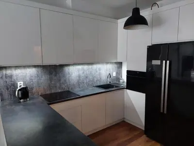 a kitchen with white cabinets and a black refrigerator at Apartament Reformacka in Wieliczka