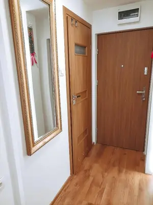 a hallway with a wooden door and a mirror at Apartament 44 in Wadowice