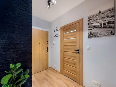 a hallway with a wooden door and a black brick wall at Apartament z dużym tarasem w centrum Krakowa in Kraków
