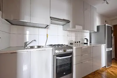 a kitchen with white cabinets and a stove and a sink at Urban Nest Apartments Starowiślna 95 in Kraków