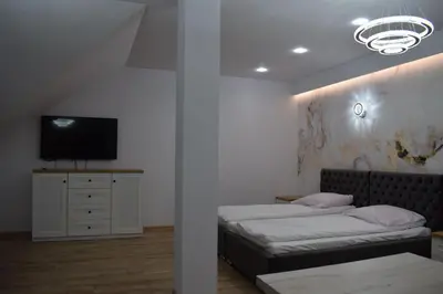 a bedroom with two beds and a tv on a wall at Mały Książę in Podzamcze
