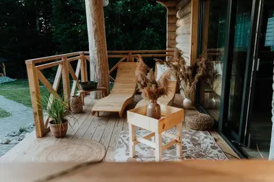 a wooden deck with a bench and chairs on it at Chałupy w Lesie Skawinki in Skawinki