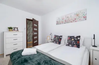a white bedroom with two beds and a dresser at Apartment Home Office Dobrego Pasterza Kraków by Noclegi Renters in Kraków