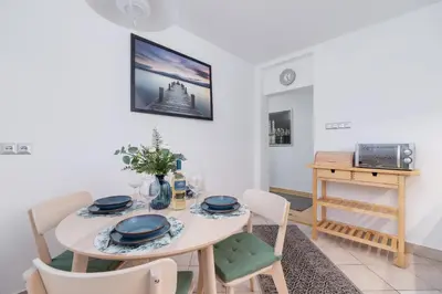 a dining room with a white table and chairs at Apartment Home Office Dobrego Pasterza Kraków by Noclegi Renters in Kraków