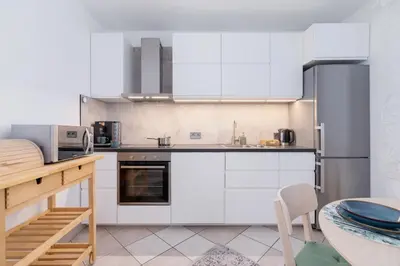 a kitchen with white cabinets and a table at Apartment Home Office Dobrego Pasterza Kraków by Noclegi Renters in Kraków