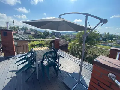 a wooden deck with a table and an umbrella at Apartament Polański z tarasem na dachu in Rabka