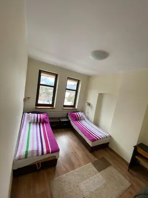two beds in a room with two windows at Apartament Polański z tarasem na dachu in Rabka