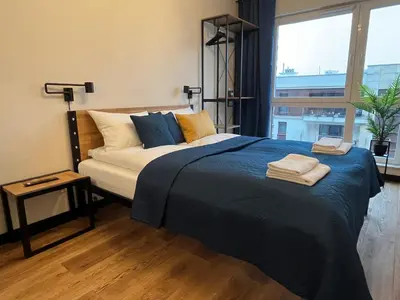 a bedroom with a bed with blue sheets and a window at PM. Apartments Krakow in Kraków