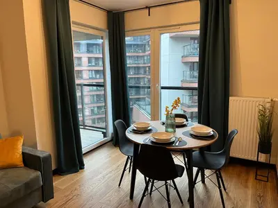 a dining room with a table and chairs in front of a window at PM. Apartments Krakow in Kraków