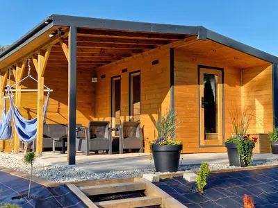 a wooden house with a porch with chairs and plants at Bulwary Mszańskie - Pokoje in Mszana Dolna