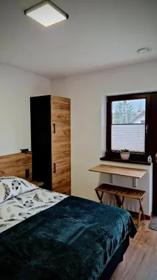 a bedroom with a bed and a desk and a window at Bulwary Mszańskie - Pokoje in Mszana Dolna