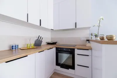 a kitchen with white cabinets and a black oven at Tauron Arena Premium Apartment with Underground & Outdoor Parking by Renters Prestige in Kraków