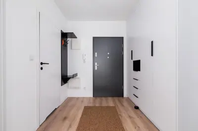 a hallway with white walls and a black door at Tauron Arena Premium Apartment with Underground & Outdoor Parking by Renters Prestige in Kraków