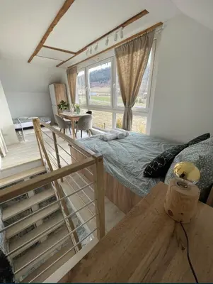 a bedroom with a bed and a staircase and a table at Domek z Widokiem Na Bliżniaki in Chocznia
