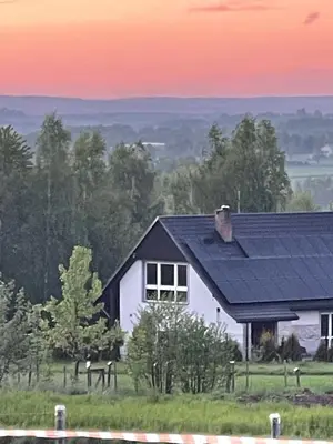 a white house with a black roof in a field at Domek z Widokiem Na Bliżniaki in Chocznia