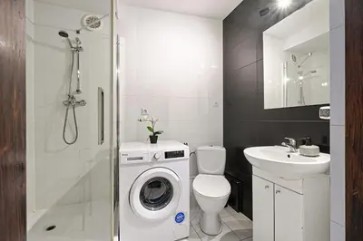 a bathroom with a toilet a sink and a washing machine at Urban Nest Apartments Augustiańska 4 in Kraków