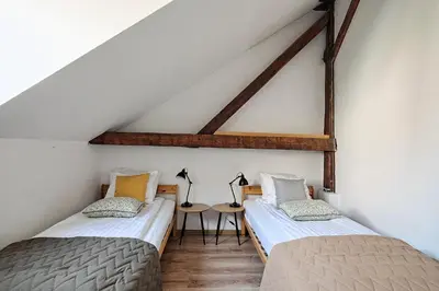 two beds in a attic room with a table at Urban Nest Apartments Augustiańska 4 in Kraków